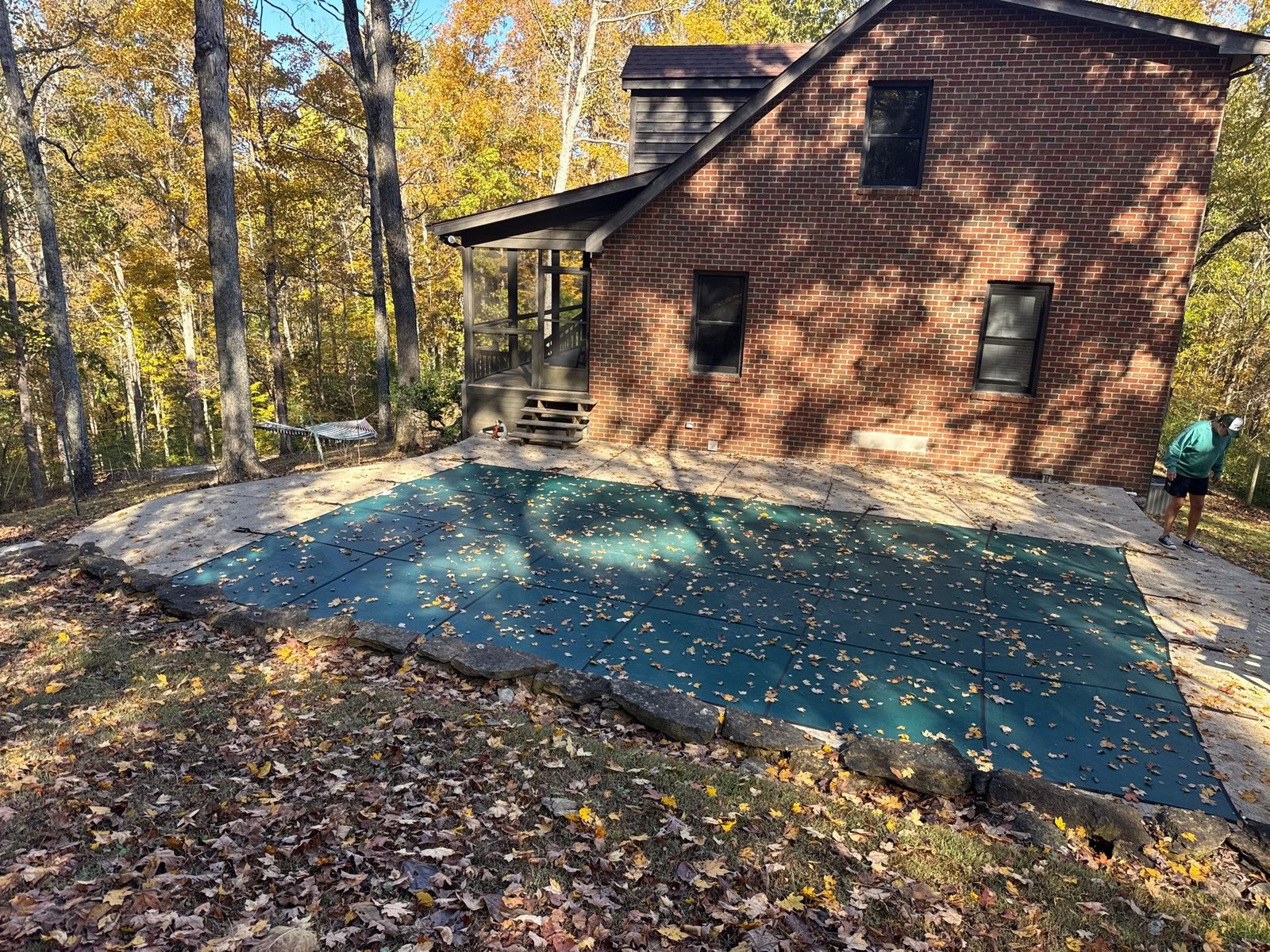 Same Ashland City pool deck before work, weathered gray concrete strewn with leaves